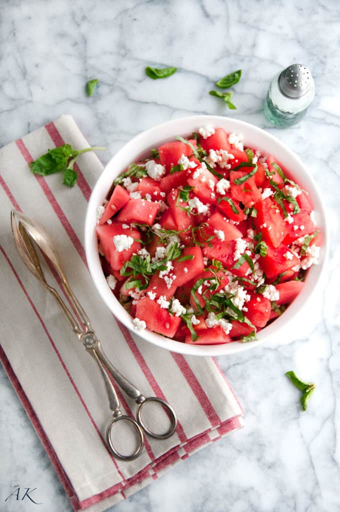 Summertime Basil Watermelon and Goat Cheese Salad with red striped towel and serving tongs