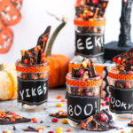 Halloween Chocolate Candy Bark in mason jars with pumpkin garland hanging in background