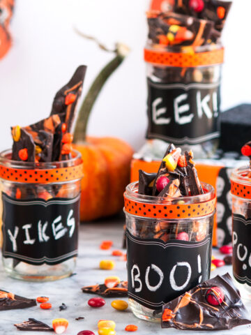 Halloween Chocolate Candy Bark in mason jars with pumpkin garland hanging in background
