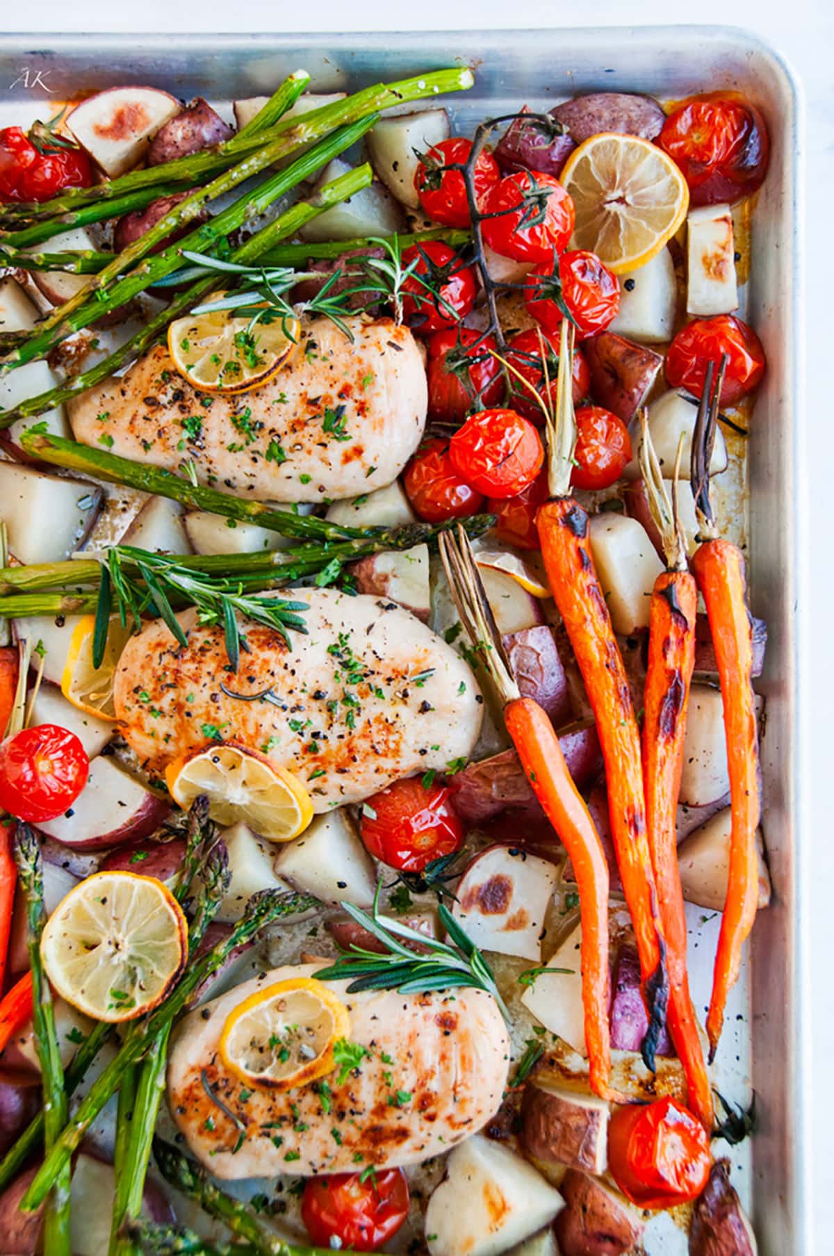 One Pan Lemon Herb Chicken on sheet pan with fresh veggies on white marble overhead view