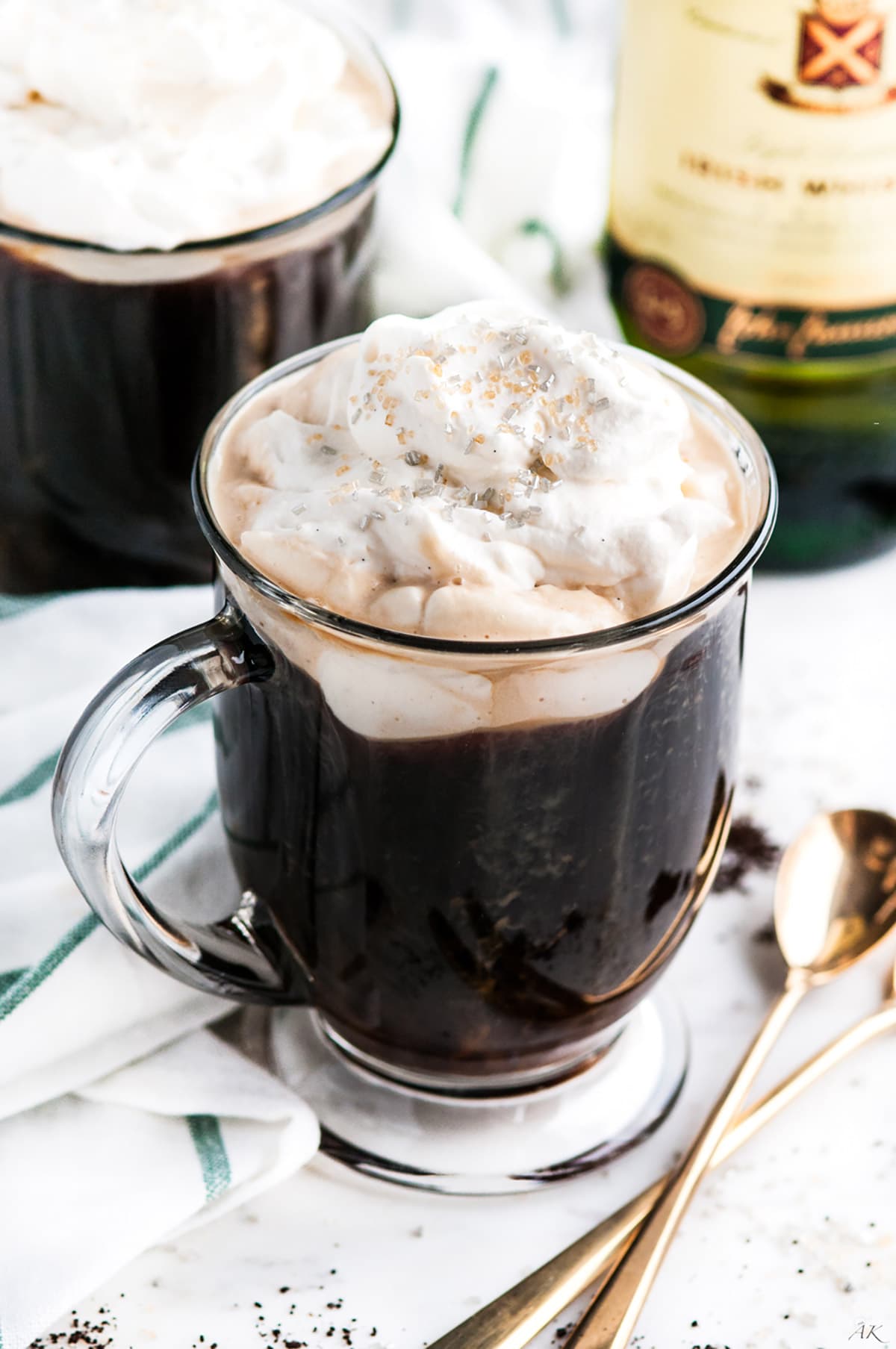 Irish Coffee with Baileys Whipped Cream in glass mugs with gold spoons with Jameson whiskey bottle in the background