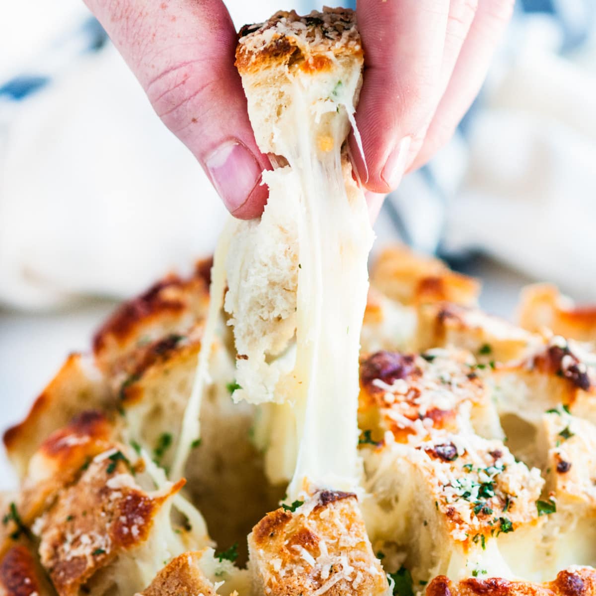 Cheesy Garlic Herb Pull Apart Bread sliced with cheesy piece pulled out by hand