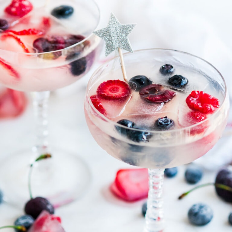 Coconut Daiquiris with Coconut Berry Ice Cubes in crystal glasses with star toothpicks on white marble