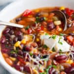Slow Cooker Three Bean Chili in white bowl with silver ladle spoon