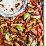 Sheet Pan Chicken Fajitas on sheet pan with tortillas in foil on white marble overhead view