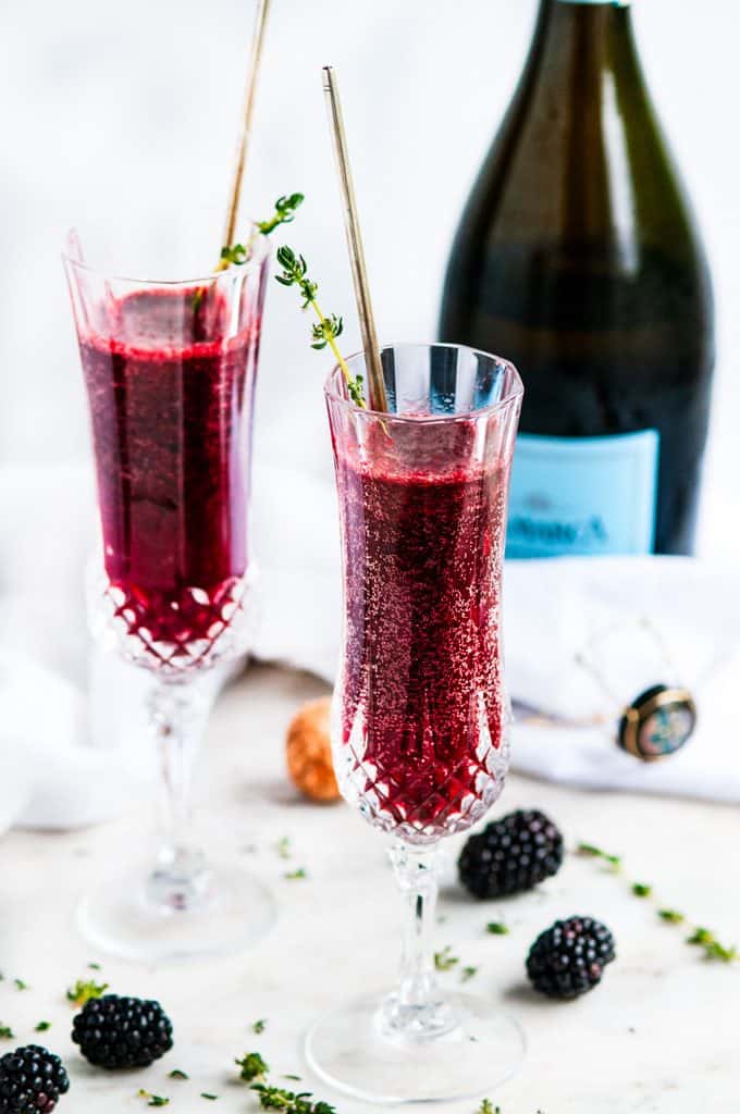 Blackberry bellini in champagne flutes with thyme and a bottle of prosecco