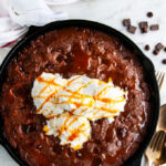 Chocolate Caramel Skillet Brownie in lodge cast iron skillet with vanilla ice cream and gold utensils