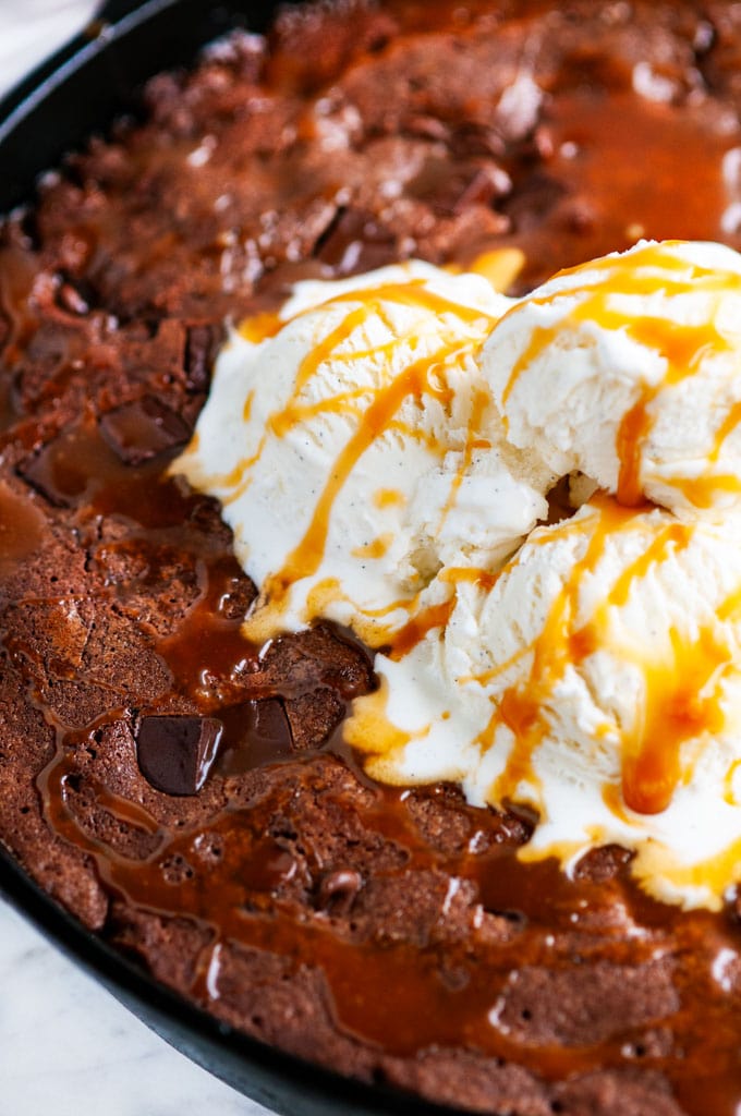 Chocolate Caramel Skillet Brownie in lodge cast iron skillet with vanilla ice cream close up