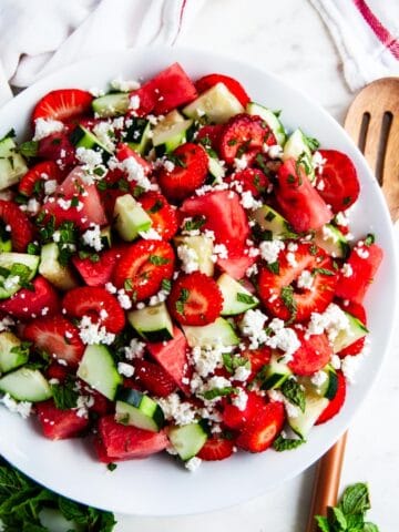 Watermelon Strawberry Cucumber Salad with wooden serving spoon and towel