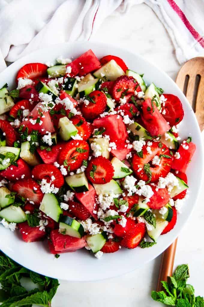 Watermelon Strawberry Cucumber Salad with wooden serving spoon and towel