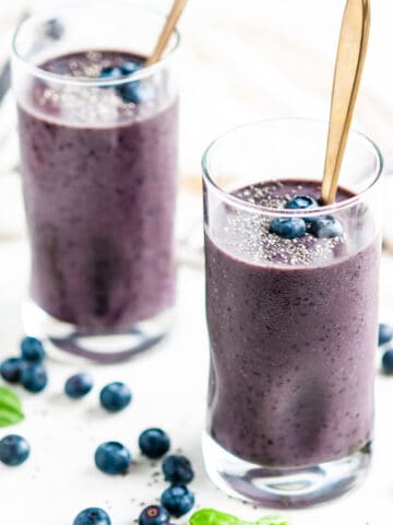 Blueberry Spinach Smoothie in glasses with gold spoons