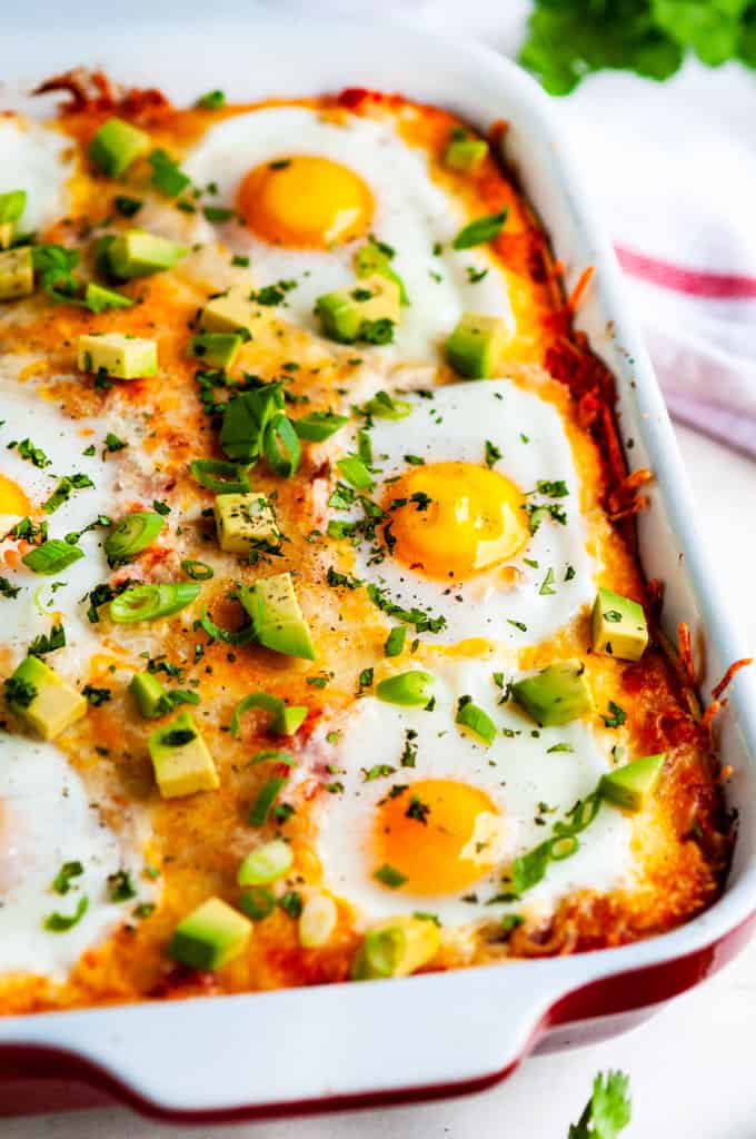 Cheesy Baked Huevos Rancheros Casserole in red dish with towel