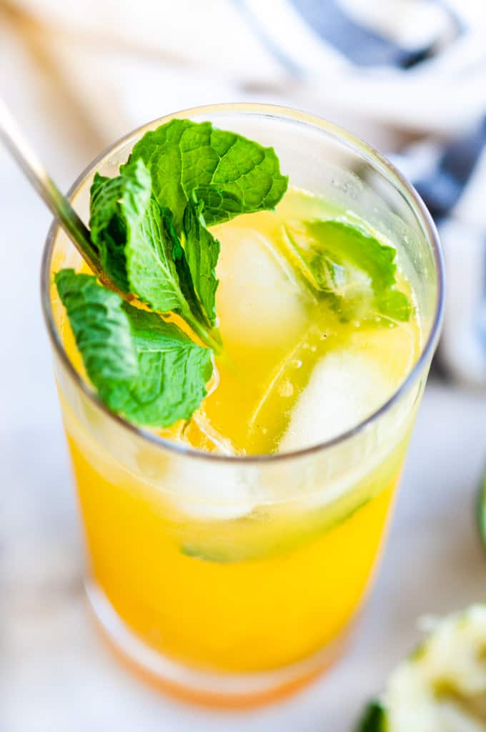 Fresh Mint Mango Mojito glass with limes and gold spoon