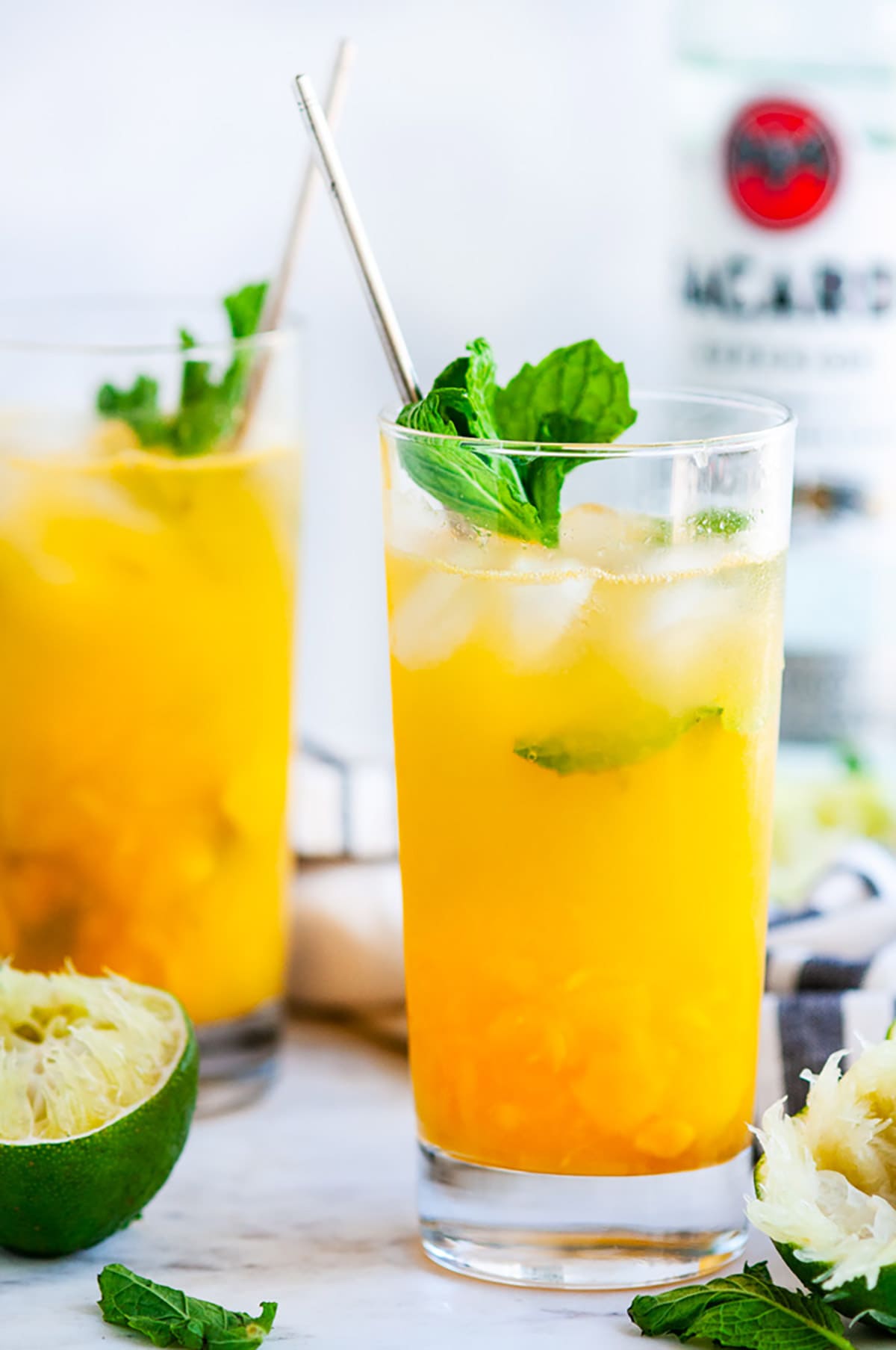 Fresh Mint Mango Mojito glasses with limes and gold spoons