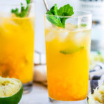 Fresh Mint Mango Mojito glasses with limes and gold spoons