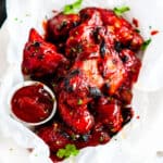 Baked Honey BBQ Chicken Wings on parchment with cilantro honey and bbq sauce