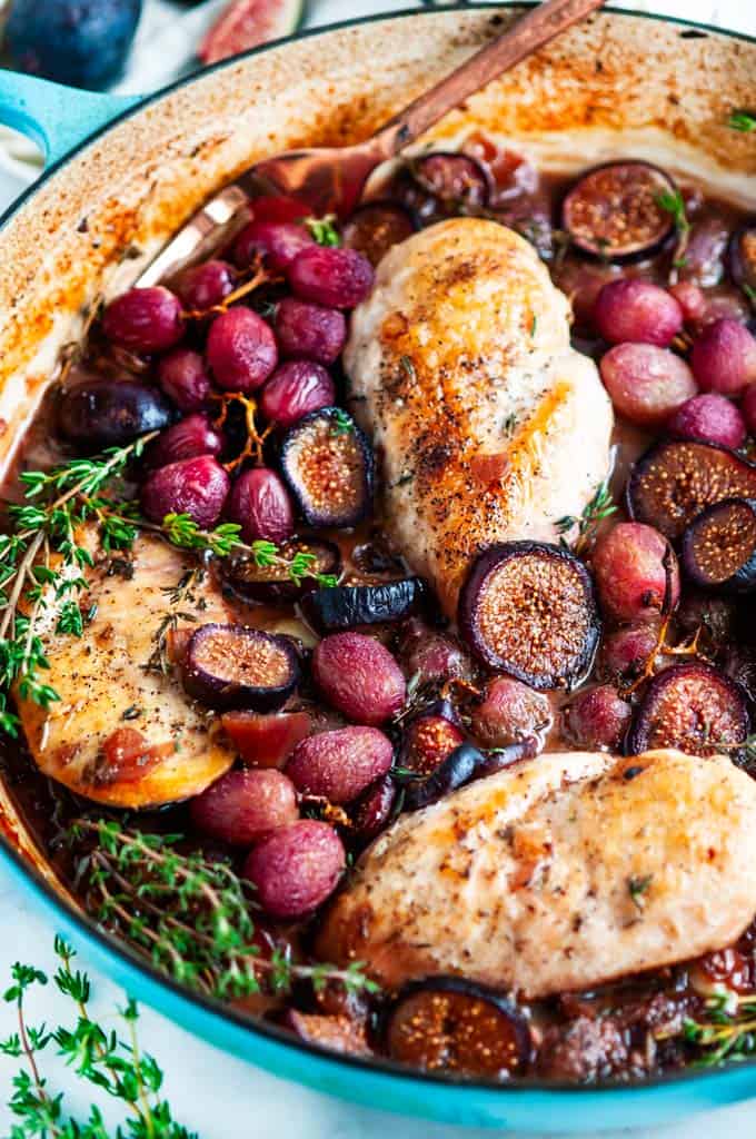 Braised Chicken with Figs and Grapes in blue le creuset braiser with fresh thyme