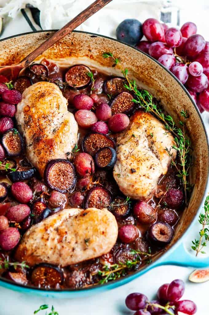 Braised Chicken with Figs and Grapes in blue le creuset braiser with fresh thyme 