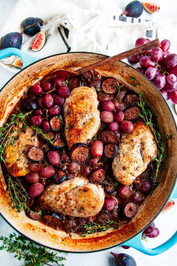 Braised Chicken with Figs and Grapes in blue le creuset braiser with fresh thyme 