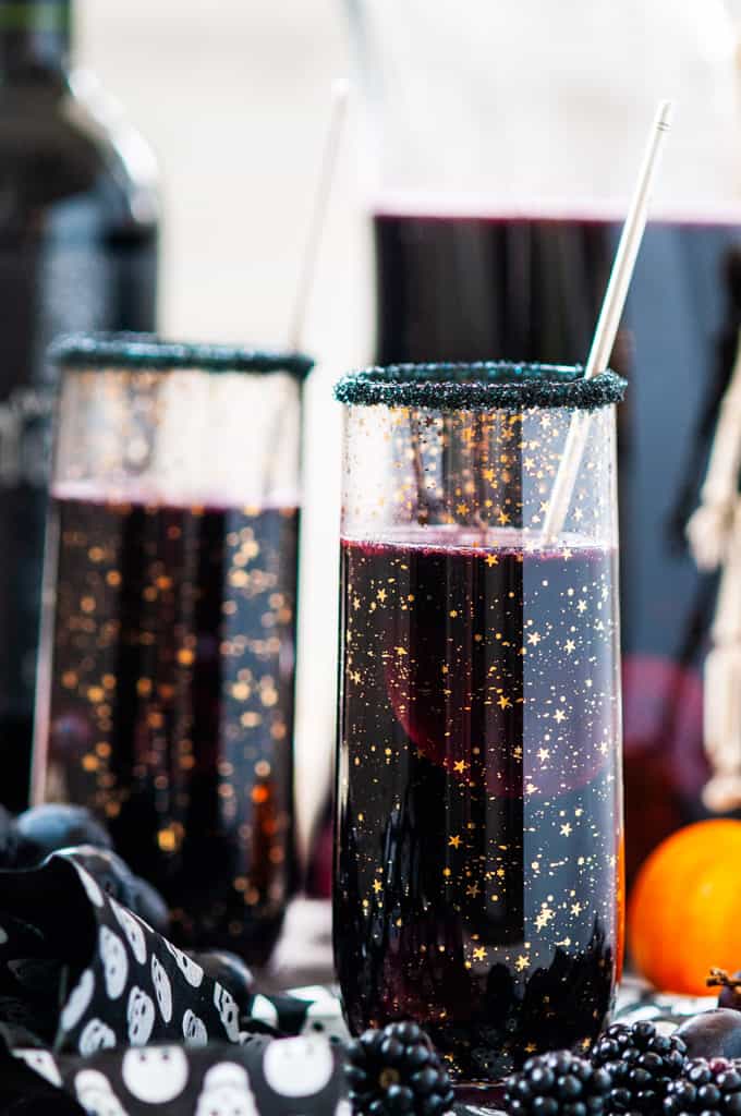 Halloween Witches Brew Black Sangria in gold sparkle star glasses with skull paper, pumpkins and pitcher