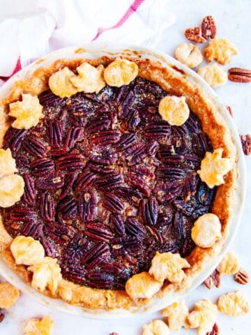 Deep dish bourbon pecan pie on marble with white towel red stripe