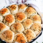 Rosemary Garlic Dinner Rolls in lodge cast iron skillet with parchment paper and white towel