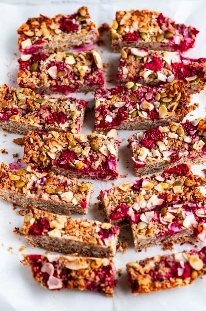 Healthy Raspberry Coconut Granola Bars on white marble with parchment paper