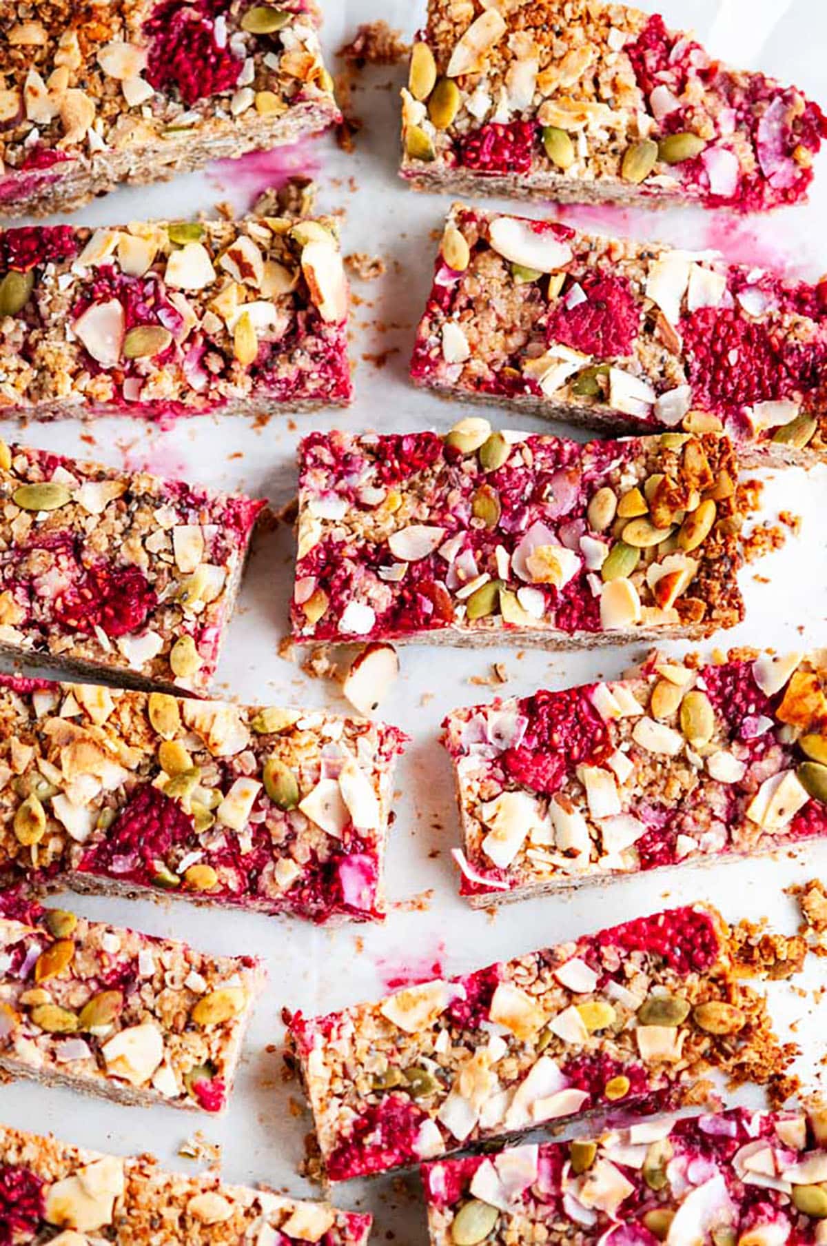 Healthy Raspberry Coconut Granola Bars on white marble with parchment paper