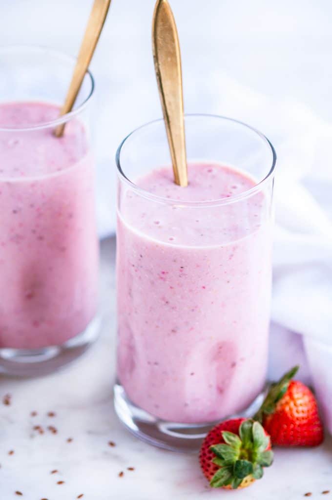 Strawberry Banana Oat Smoothie tall glasses with gold spoons