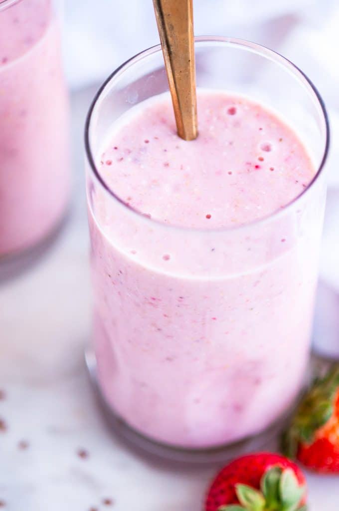 Strawberry Banana Oat Smoothie tall glasses with gold spoons