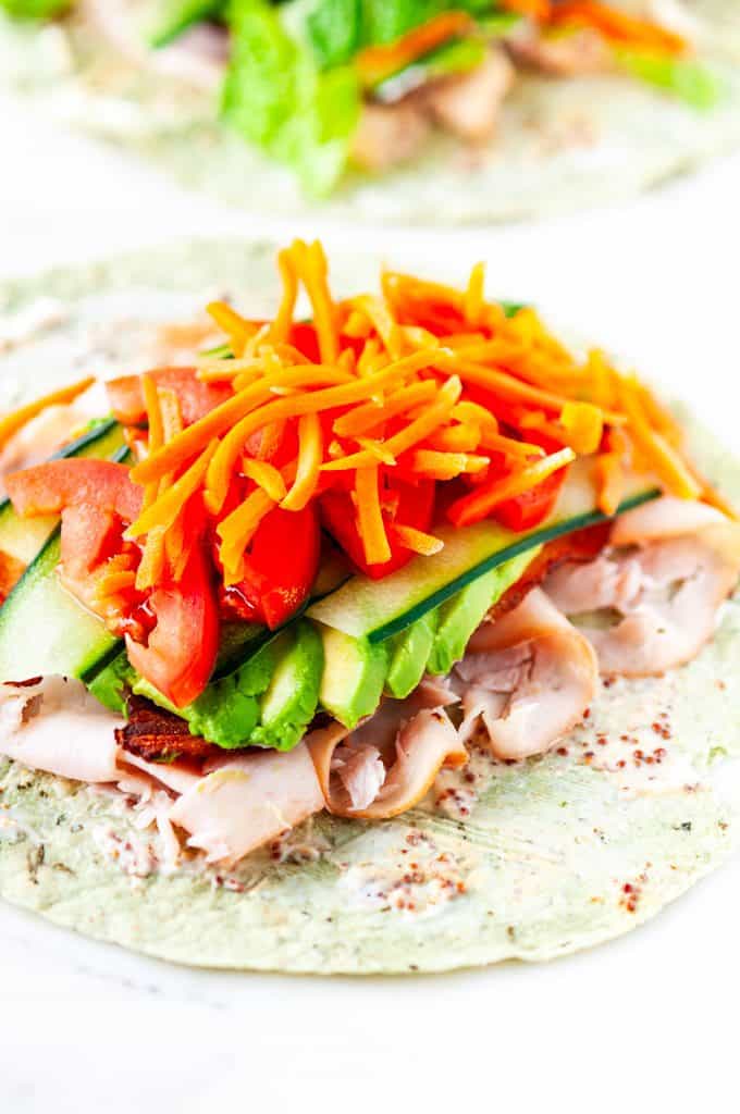 Turkey BLT wraps with shredded lettuce and carrots on white marble