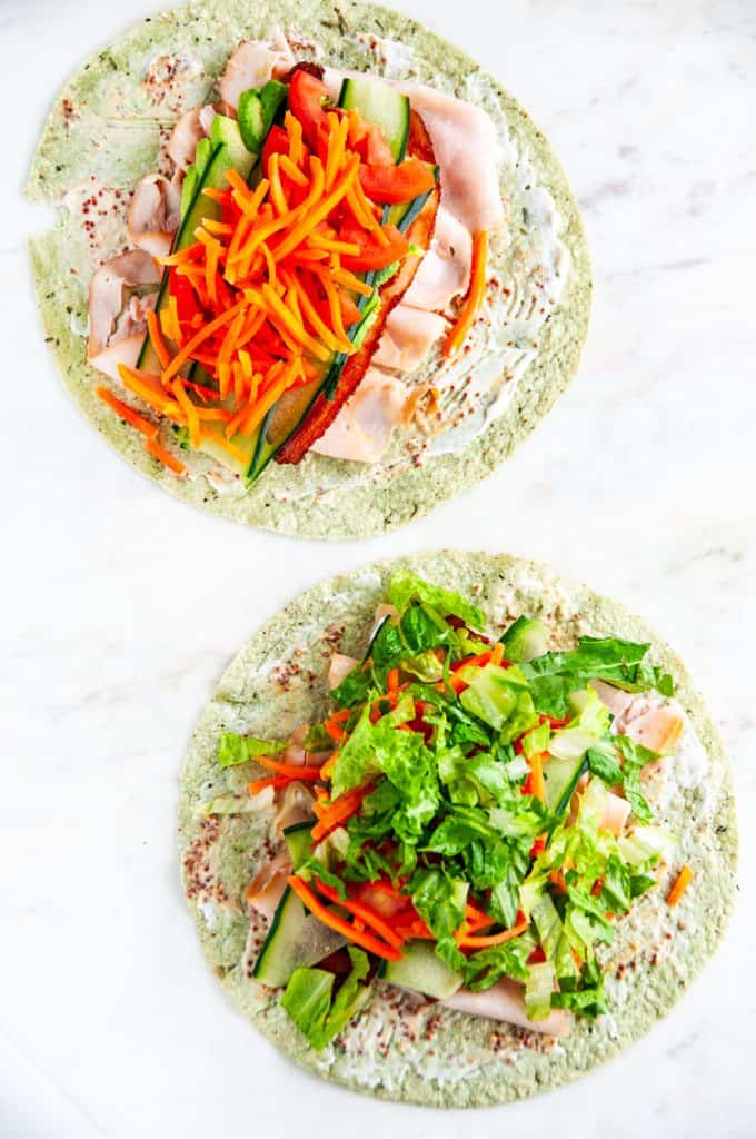 Turkey BLT wraps with shredded lettuce and carrots on white marble
