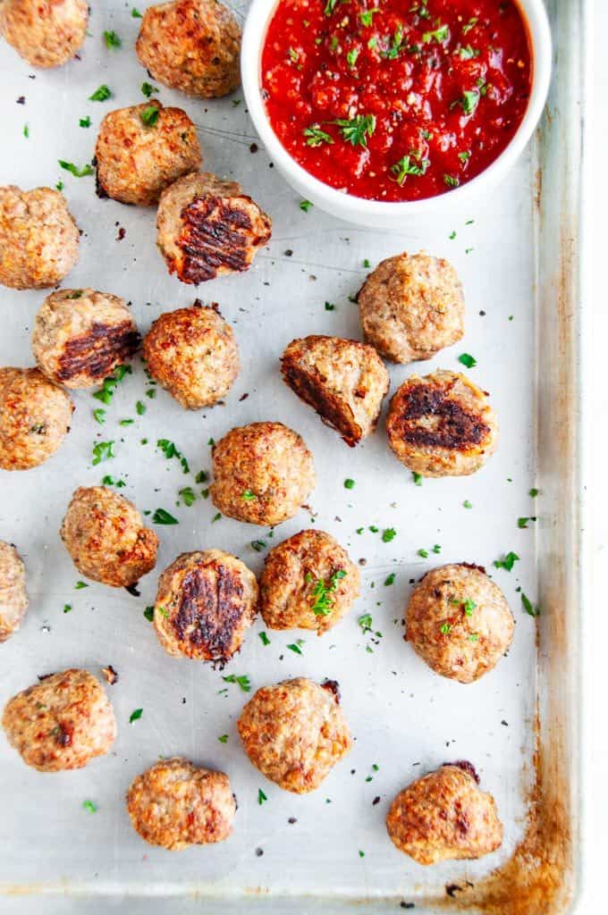 Baked Turkey Meatballs on sheet pan with parchment paper and marinara dipping sauce