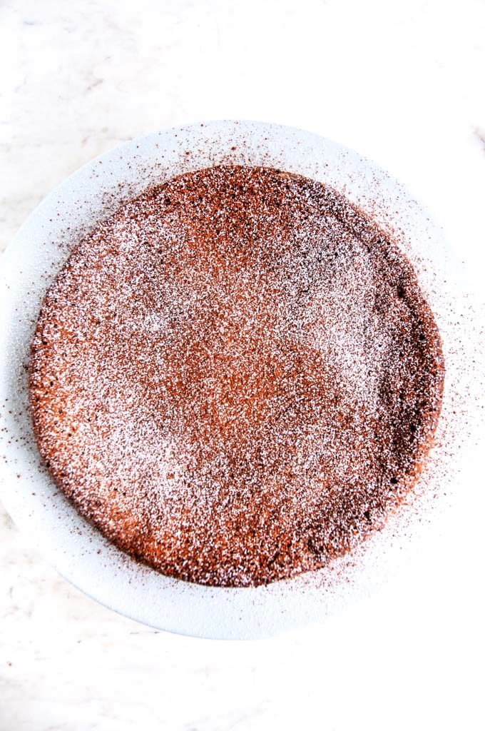 Flourless Chocolate Torte dusted with cocoa powder and powdered sugar on white marble