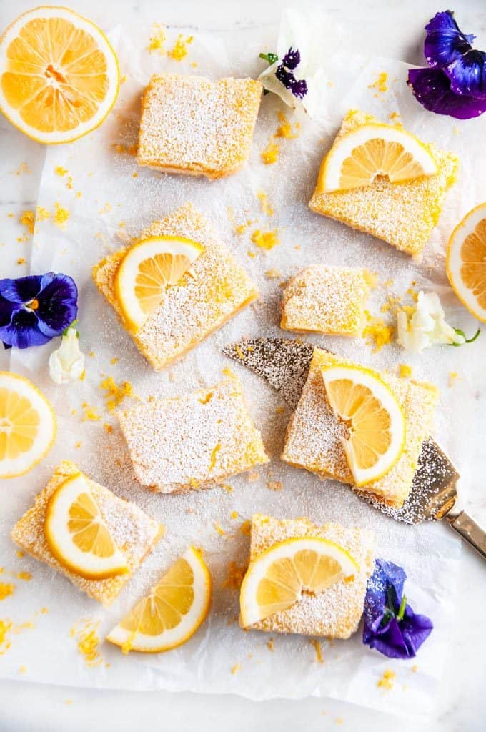 Best Ever Classic Lemon Bars with gold pie server and edible purple and white flowers