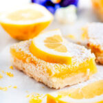 Best Ever Classic Lemon Bars sliced piece on white marble close up