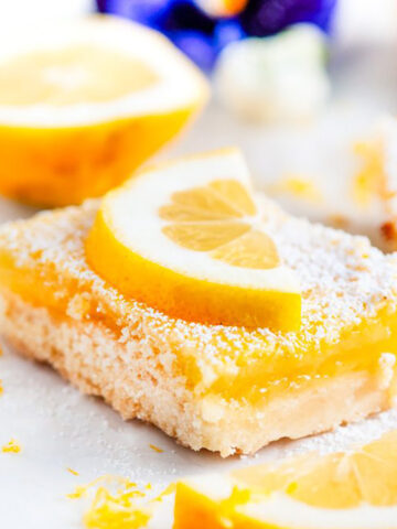 Best Ever Classic Lemon Bars sliced piece on white marble close up