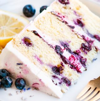Lemon Blueberry Lavender Cake with Mascarpone Buttercream Frosting slice on white plate with gold fork