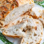 No Knead Rosemary Garlic Bread sliced on marble with fresh rosemary