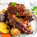Mole braised beef short ribs on gray plate with roasted potatoes and tea towel
