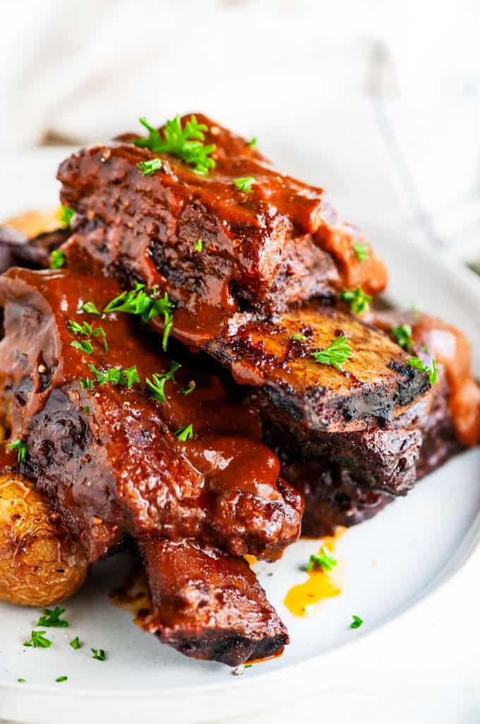 Mole braised beef short ribs on gray plate with roasted potatoes