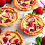 Strawberry Custard Honey Tarts with Lemon Curd on parchment paper with fresh mint