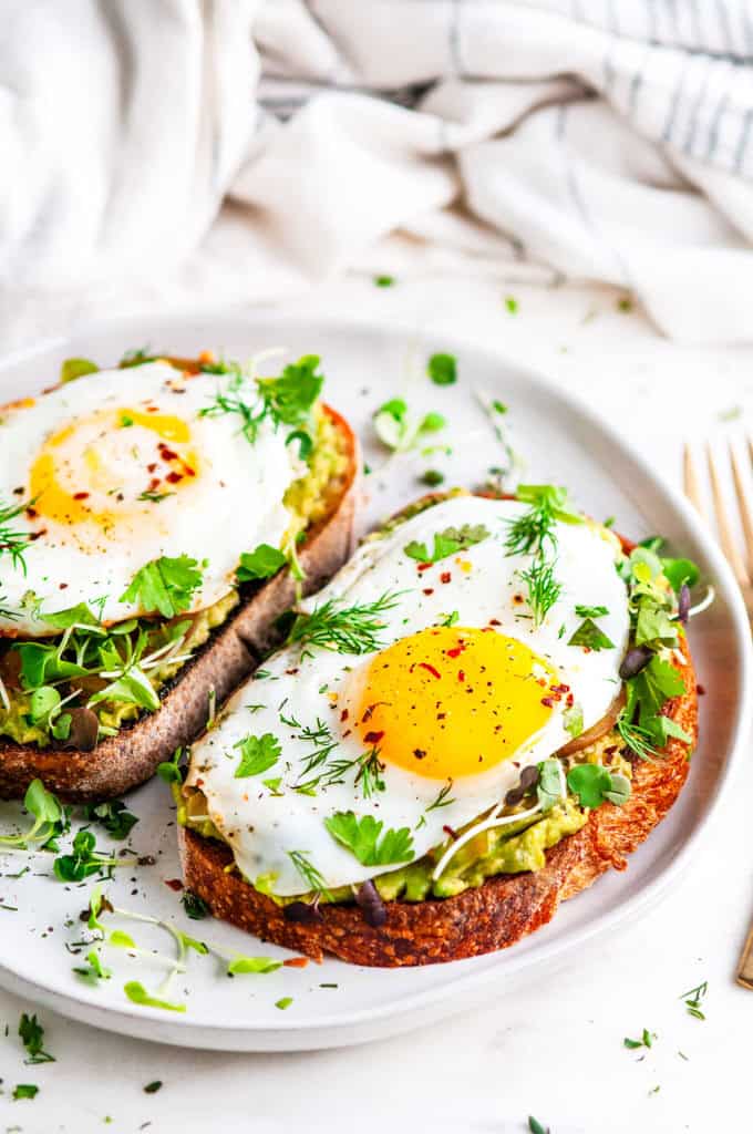 Avocado egg breakfast toast on gray plate with gold fork