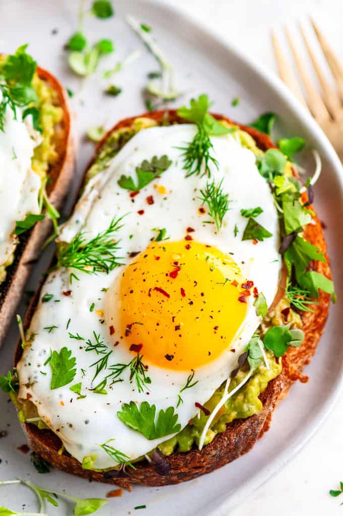 Avocado egg breakfast toast on gray plate with gold fork