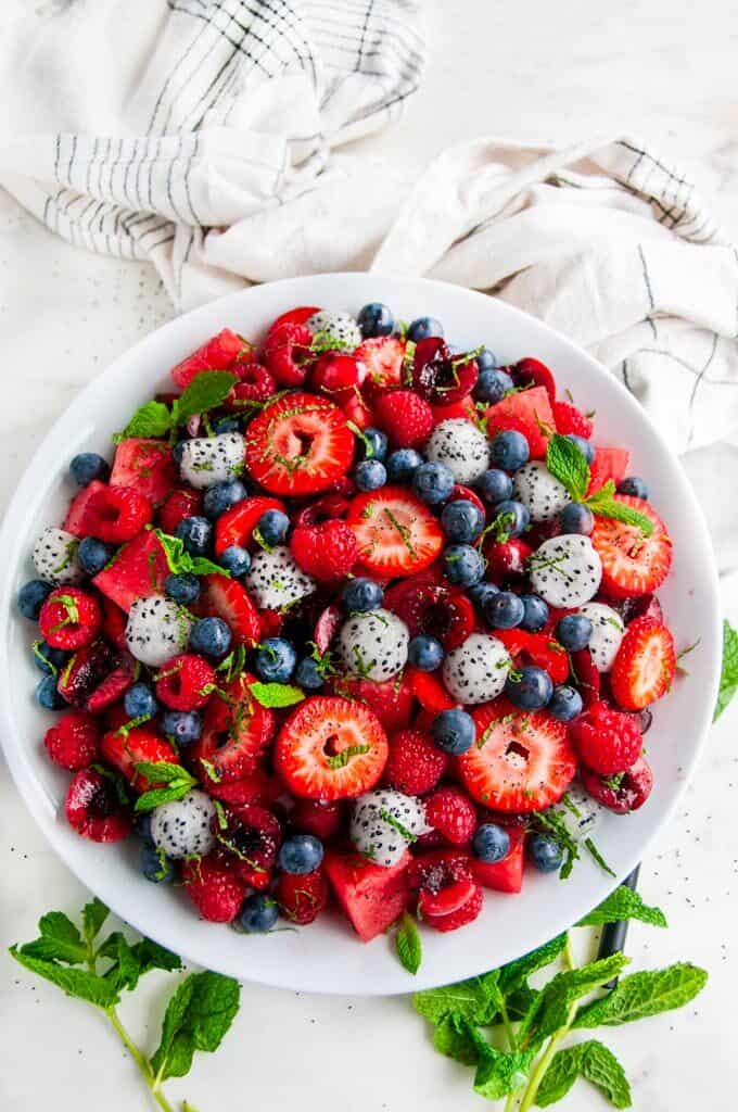 Berry Watermelon Dragon Fruit Salad with mint in white bowl on white marble