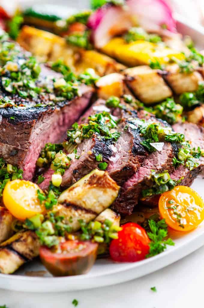 Grilled Tri Tip with Vegetables and Chimichurri Sauce on gray plate close up