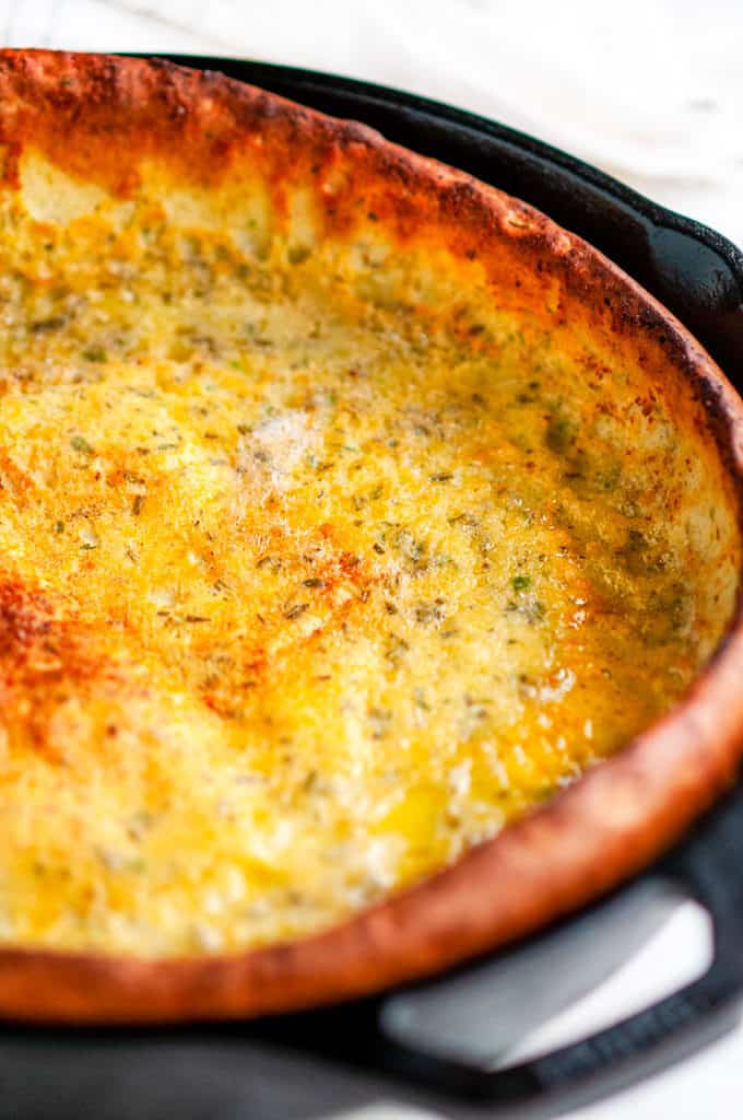 Savory Herb Cheddar Dutch Baby lodge cast iron skillet on white marble close up