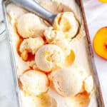 No Churn Peaches and Cream Ice Cream with gray scoop and tea towel on white marble