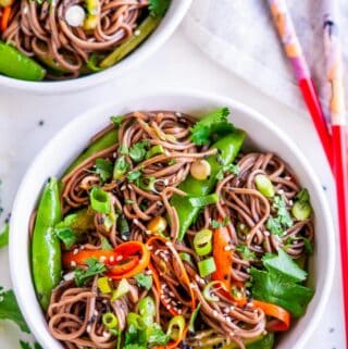 Soba Noodle Salad with Sesame Soy Dressing white bowl with cilantro, tea towel, and red chopsticks