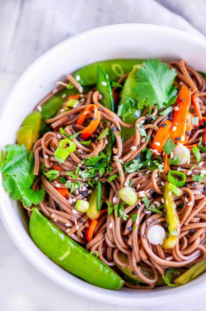 Soba Noodle Salad with Sesame Soy Dressing white bowl with cilantro, tea and tea towel